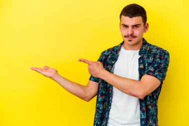 Sarı arka planda izole edilmiş beyaz bir adam. Palmiye üzerinde bir kopya alanı tutarken heyecanlı..