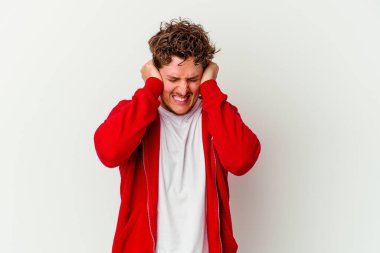 Beyaz arka planda izole edilmiş genç beyaz bir adam kulakları kulaklarıyla kapatıyor ve çok ses duymamaya çalışıyor..