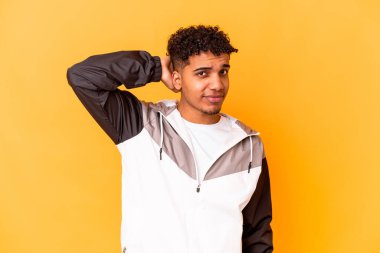 Genç Afro-Amerikan kıvırcık adamı, mor tenli, başının arkasına dokunmuş, düşünüyor ve bir seçim yapıyor..