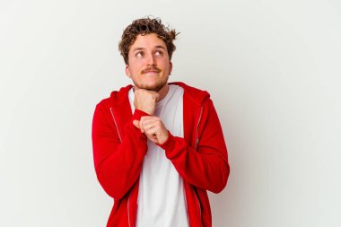 Beyaz arka planda izole genç beyaz adam ellerini çenesinin altında tutuyor, mutlu bir şekilde yana bakıyor..