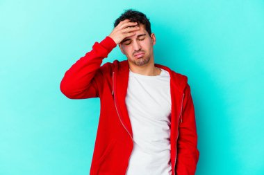 Genç beyaz adam mavi arka planda izole edilmiş tapınaklara dokunuyor ve başı ağrıyor..