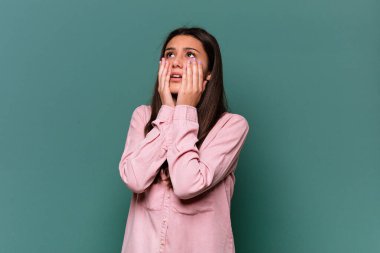 Genç Hintli bir kadın mavi arka planda yalnız başına sızlanıyor ve ağlıyor..