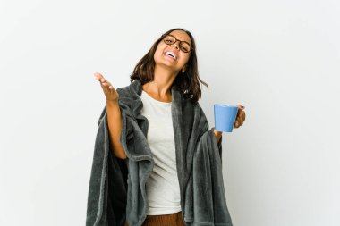 Beyaz arka planda battaniyeli genç Latin kadın kameraya sarıldığı için kendinden emin hissediyor..