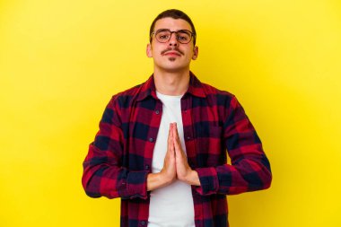 Sarı arka planda izole edilmiş genç, beyaz bir adam. Dua ediyor, bağlılık gösteriyor. İlahi ilhamı arayan dindar biri..