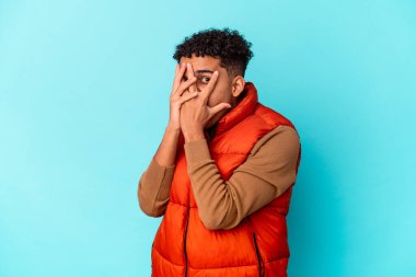 Genç Afro-Amerikalı kıvırcık adam mavi ışıkta izole edilmiş parmaklarıyla korkmuş ve gergin.