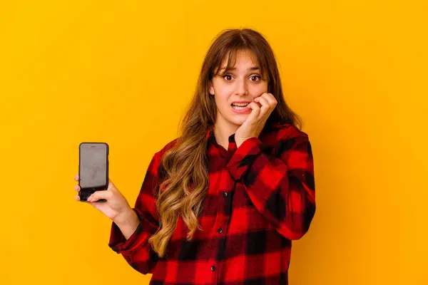 Junge Kaukasische Frau Mit Handy Isoliert Auf Gelbem Hintergrund Beißt — Stockfoto