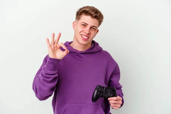 若いですCaucasian男保持Aゲームパッド隔離上の白い背景陽気で自信を持ってショーOkジェスチャー — ストック写真