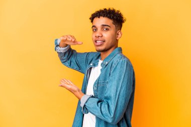 Genç Afro-Amerikan kıvırcık adamı, mor üzerine izole edilmiş, parmakları olan, gülümseyen ve kendinden emin bir şey tutuyor..
