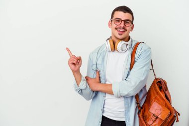 Beyaz arka planda izole edilmiş müzik dinleyen beyaz tenli genç bir öğrenci işaret parmağıyla işaret ederek gülümsüyor..