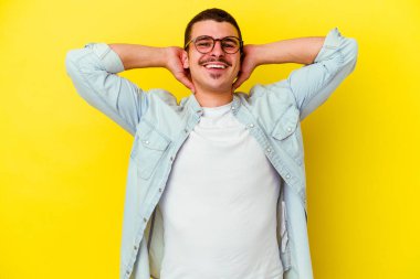 Sarı arka planda izole edilmiş, kollarını uzatan, rahat bir pozisyonda genç, beyaz bir adam..