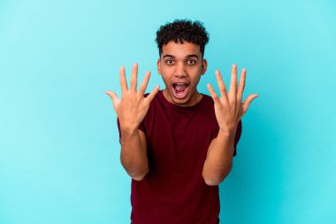 Genç Afro-Amerikan kıvırcık adamı mavi üzerine izole edilmiş. Elleriyle on numarayı gösteriyor..