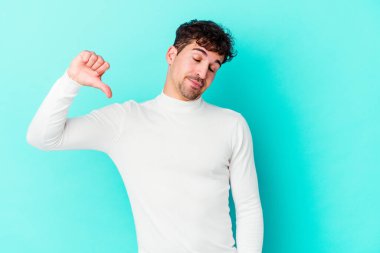 Mavi arka planda izole edilmiş genç beyaz bir adam hoşlanmadığı bir jest yapıyor. Anlaşmazlık konsepti.