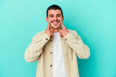 Kafkasyalı genç adam mavi arka planda izole edilmiş iki seçenek arasında şüphe duyuyor.