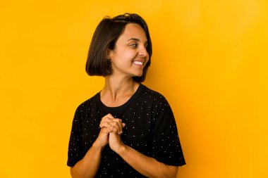 Sarı üzerine izole edilmiş genç İspanyol kadın kollarını kavuşturarak gülümsüyor..