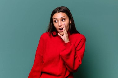 Mavi arka planda izole edilmiş genç Hintli kadın gizli bir sıcak fren haberinin olduğunu söylüyor.