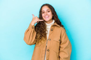 Kafkasyalı kıvırcık saçlı genç kadın izole edilmiş, parmaklarıyla bir cep telefonu hareketi gösteriyor..