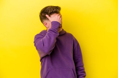 Sarı arka planda izole edilmiş genç beyaz adam ellerini başının üstünde tutarak neşe içinde gülüyor. Mutluluk kavramı.