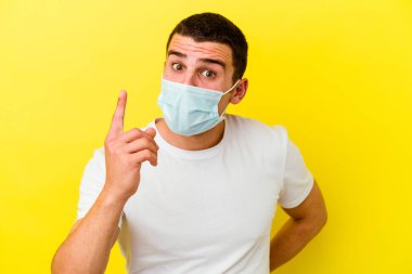 Koronavirüse karşı korunan beyaz bir adam sarı arka planda izole edilmiş bir fikir, ilham verici bir konsept..