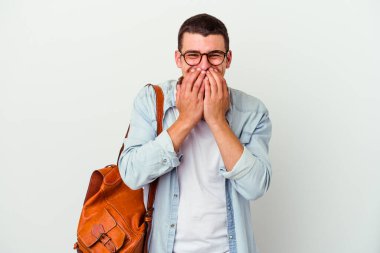 Beyaz arka planda izole edilmiş müzik dinleyen beyaz tenli genç bir öğrenci bir şeye gülüyor, elleriyle ağzını kapatıyor..