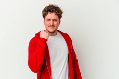 Beyaz arka planda izole edilmiş genç beyaz bir adam yumruğunu kameraya gösteriyor, agresif bir yüz ifadesi..