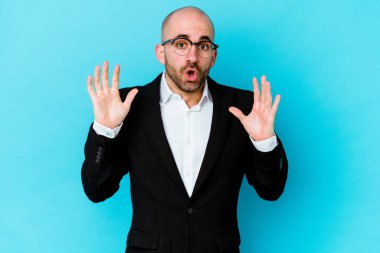 Genç, beyaz, kel bir adam mavi arka planda izole edilmiş. Bir fikri var, ilham verici bir kavram..