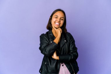 Genç melez kadın gülümsüyor mutlu ve kendinden emin, elleriyle çenesine dokunuyor..