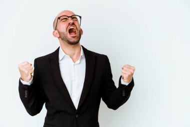 Genç, beyaz, kel bir adam mavi arka planda izole edilmiş zafer kazandıktan sonra yumruğunu kaldırıyor..