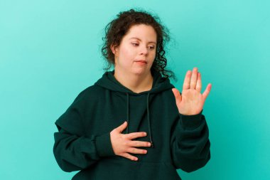 Down sendromlu bir kadın tek başına yemin ediyor ve elini göğsüne koyuyor..