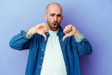 Mor arka planda soyutlanmış beyaz kel bir adam baş parmağını aşağı gösteriyor ve hoşlanmadığını ifade ediyor..