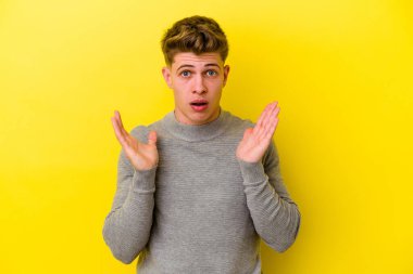 Sarı arka planda izole edilmiş genç beyaz adam şaşırdı ve şok oldu..