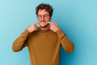 Mavi arka planda gözlüklü genç beyaz adam iki seçenek arasında kuşkulanıyor.