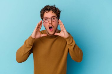 Mavi arka planda izole edilmiş gözlüklü beyaz bir adam heyecanlı bir şekilde öne doğru bağırıyor..