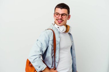 Beyaz arka planda izole edilmiş müzik dinleyen beyaz tenli genç bir öğrenci gülümseyen, neşeli ve keyifli bir kenara bakar..