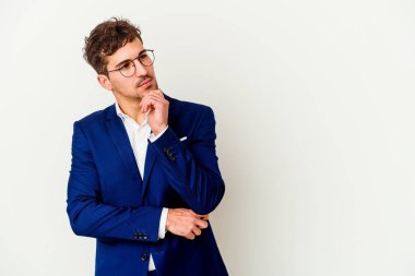 Beyaz arka planda izole edilmiş beyaz iş adamı şüpheli ve şüpheci bir ifadeyle yana bakıyor..