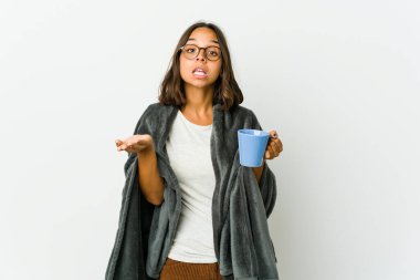 Beyaz arka planda battaniyesi olan genç Latin kadın kollarıyla ölçek oluşturuyor, mutlu ve kendinden emin hissediyor..