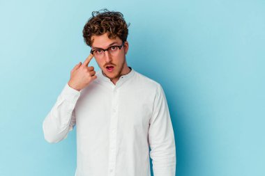 Kafkasyalı genç iş adamı mavi arka planda izole edilmiş işaret parmağıyla bir hayal kırıklığı jesti gösteriyor..