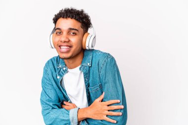 Genç Afro-Amerikalı kıvırcık adam kulaklıklarla müzik dinleyip gülüyor ve eğleniyor..