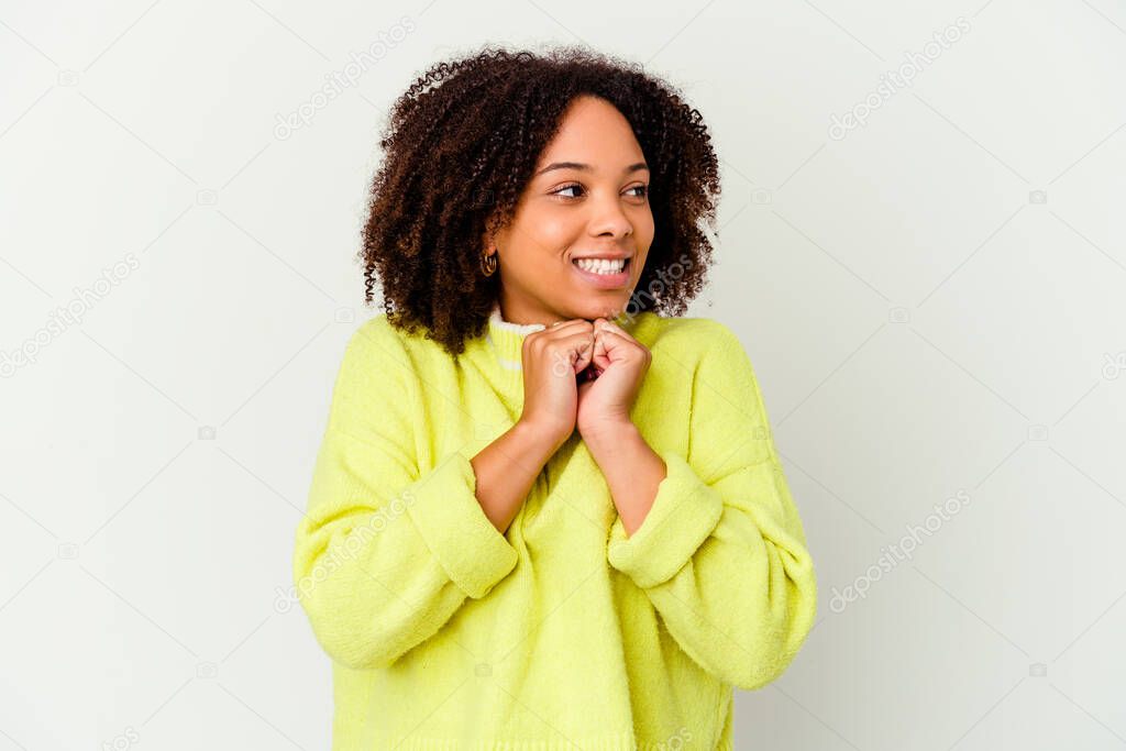 Young african american mixed race woman isolated keeps hands under chin, is looking happily aside.