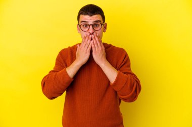 Sarı arka planda izole edilmiş beyaz bir adam elleriyle ağzını kapatırken şok oldu..