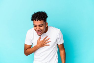 Genç Afro-Amerikalı kıvırcık adam mavi üzerine izole edilmiş kahkahalar atıyor..