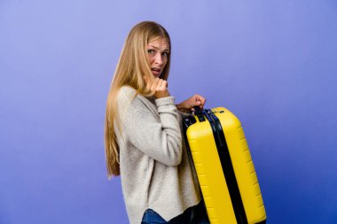 Korkmuş ve korkmuş bir şekilde seyahat etmek için bavul tutan genç bir Rus kadın..