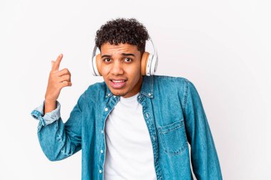 Genç Afro-Amerikalı kıvırcık adam kulaklıkla müzik dinleyip işaret parmağıyla yaptığı hayal kırıklığı jestini gösterdi..