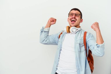 Beyaz arka planda müzik dinleyen beyaz tenli genç bir öğrenci zaferden sonra yumruğunu kaldırıyor..