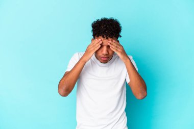 Genç Afro-Amerikalı kıvırcık adam mavi üzerine izole edilmiş, başı ağrıyor, yüzüne dokunuyor..