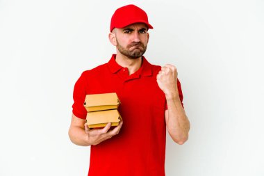 Beyaz arka planda izole edilmiş beyaz tenli genç teslimatçı yumruğunu kameraya gösteriyor, agresif yüz ifadesi..