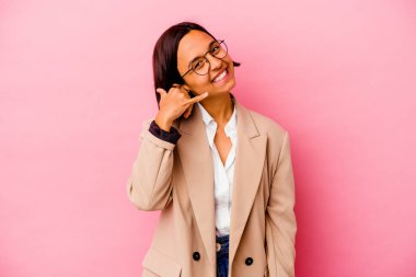 Pembe arka planda izole edilmiş genç iş kadını parmakları ile bir cep telefonu çağrı jesti gösteriyor.