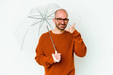 Şemsiyesi olan kel bir genç, parmaklarıyla bir cep telefonu hareketi gösteriyor..