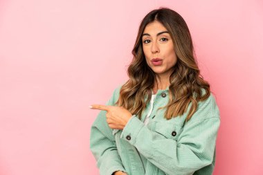 Kafkasyalı genç bir kadın kendini izole edip gülümsüyor ve boş alanda bir şeyler gösteriyor..