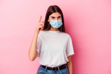 Pembe arka planda izole edilmiş virüs maskesi takan beyaz bir kadın. Bir fikri, ilham verici bir fikri var..