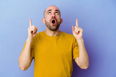 Mor arka planda izole edilmiş beyaz kel bir adam ağzı açık bir şekilde üst tarafı işaret ediyor..